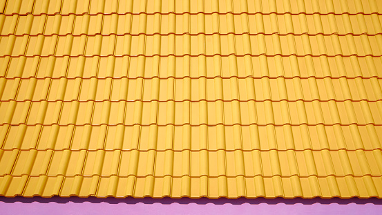 Yellow ceramic tile roof on top of pink modern house with sunlight on surface in widescreen view