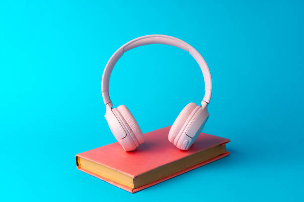 istock Pink headphones on a book on blue background 1694045335