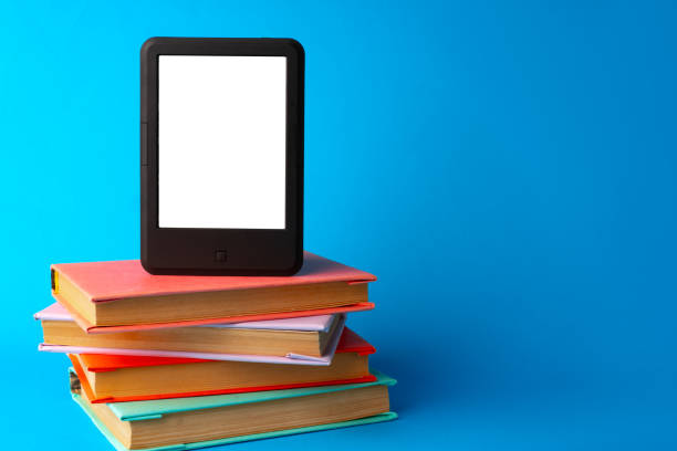 istock Modern e-book on stack of hardcover books on blue background 1694045339