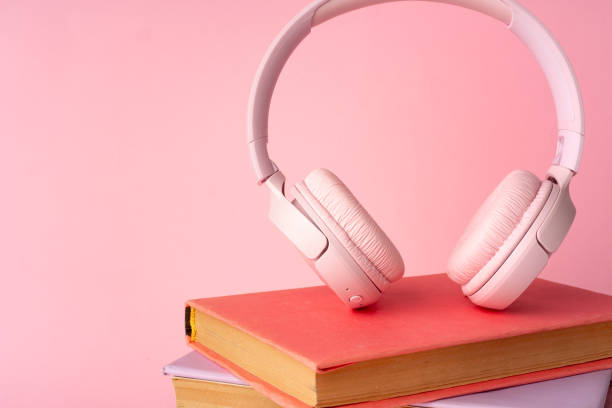 istock Pink headphones on a book on blue background 1694045403