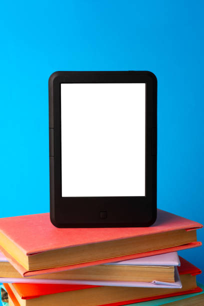 istock Modern e-book on stack of hardcover books on blue background 1694049837