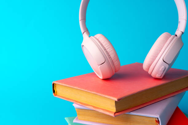 istock Pink headphones on a book on blue background 1694050357