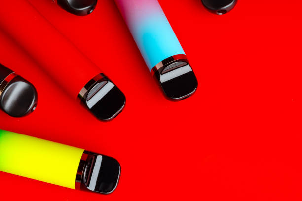istock Colorful disposable electronic cigarettes on red background 1694050917