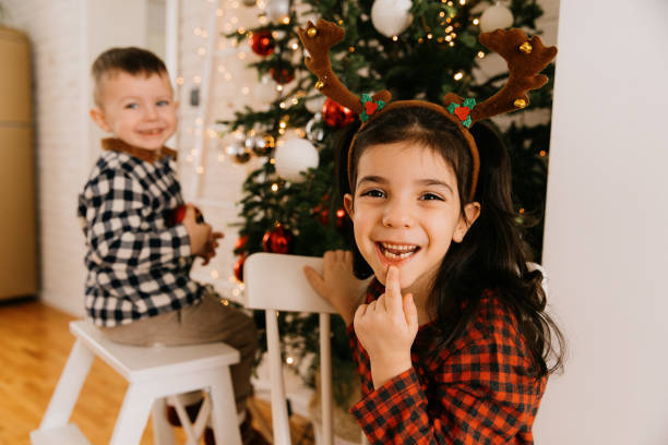 istock Cheerful children having fun in front of Christmas tree 1694063117