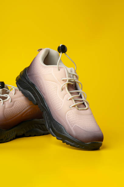 istock Beige sport running shoes on yellow studio background 1694063661
