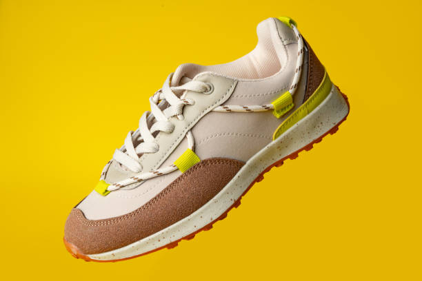 istock Beige sport running shoes on yellow studio background 1694063662