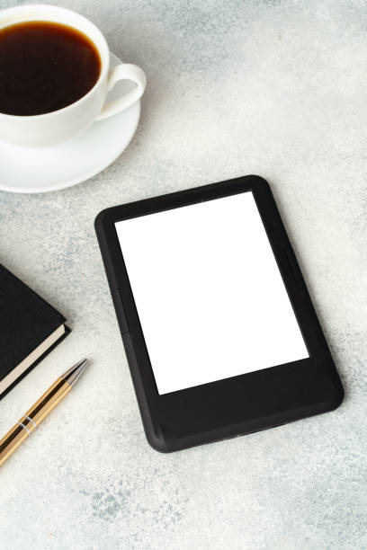istock Composition with modern e-book reader, hardcover book and cup of coffee on table 1694068679