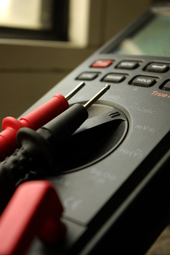 Vertical shot of an electrical and electronics measurement device with black and red probes used for control, maintenance, repair, diagnostic and measurement
