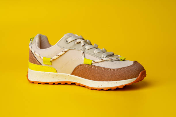 istock Beige sport running shoes on yellow studio background 1694077490