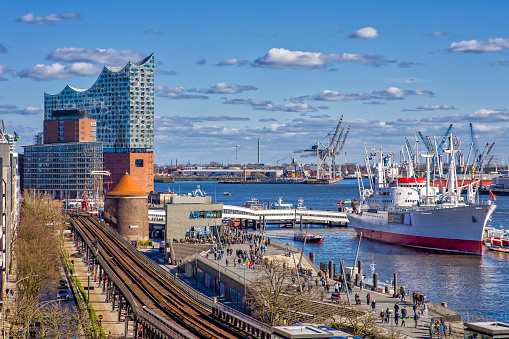 view of hamburg and the elbe river with the elbphilharmonie concert hall and harbor area under a slightly cloudy sunny sky