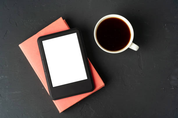 istock Composition with modern e-book reader, hardcover book and cup of coffee on table 1694083548