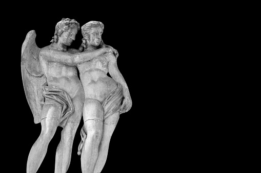 Cupid and Psyche. An ancient stone statue on black background. Copy space.