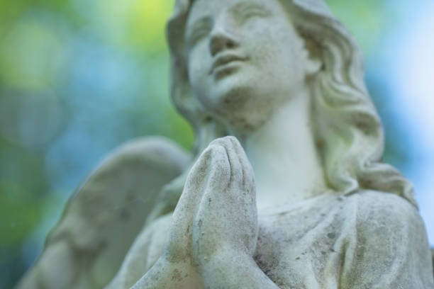 Tender beautiful angel praying. Fragment of an  ancient statue. Selective focus on hands. Horizontal image.