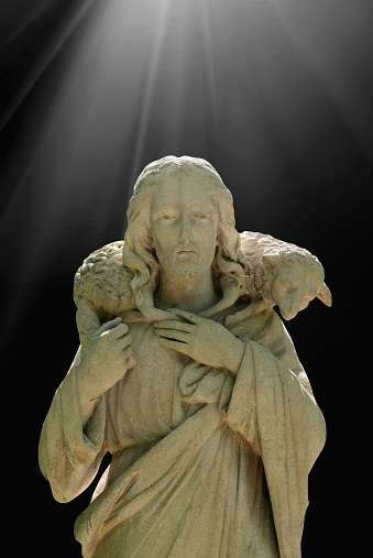 Antique statue of Jesus Christ Good Shepherd in the rays of light. In the Christian tradition, a symbol of human importance to God.