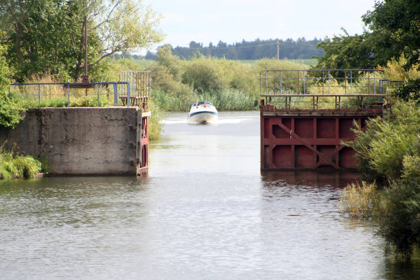 Motor boat. Open river gate. River name is Minija. Motor boat sails through the gates. Calm river
