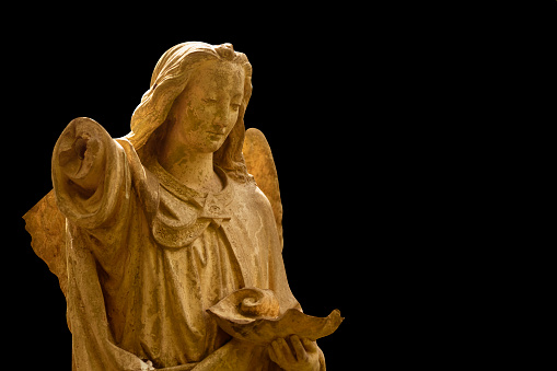 Fragment of an ancient statue of beautiful angel against black background. Copy space.