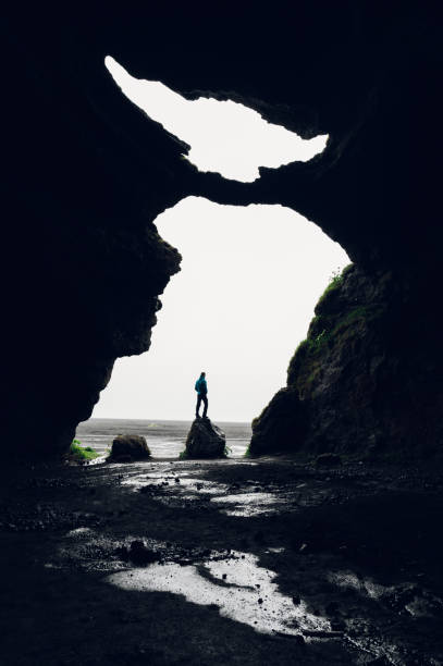 istock A man standing on a rock in a cave entry in nature in Iceland. 1694103176