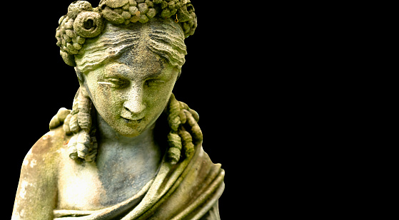 Goddess Hera. Fragment of an ancient statue isolatedon  black background. Copy space.