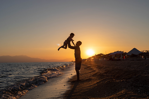 A wonderful picture of a father and daughter's favorite game. The father holds the child high and spins her around as the beautiful sun shines on them.