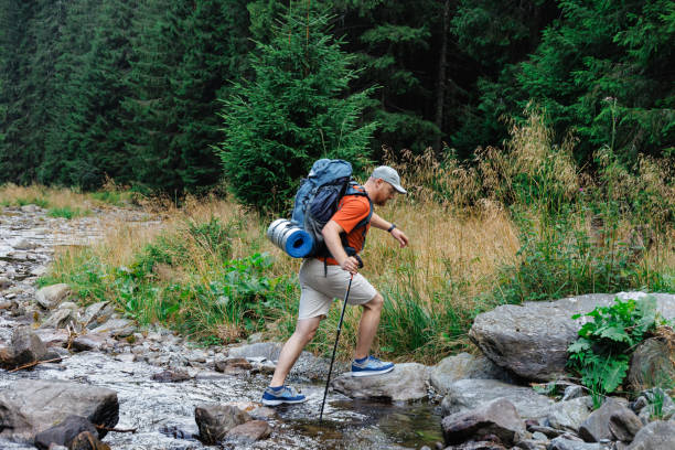 istock Male hiker crossing creek in forest 1694145035