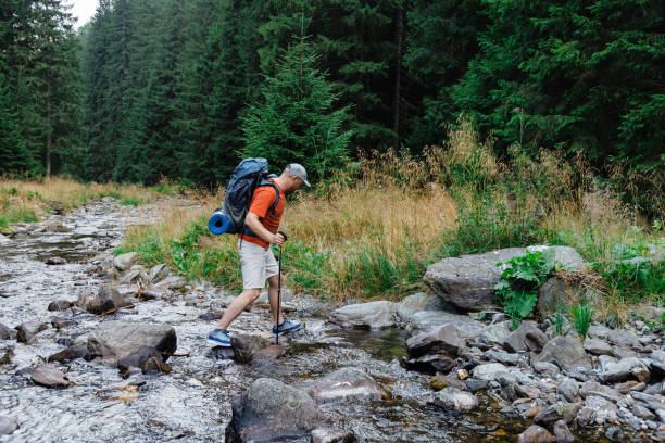 istock Male hiker crossing creek in forest 1694145046
