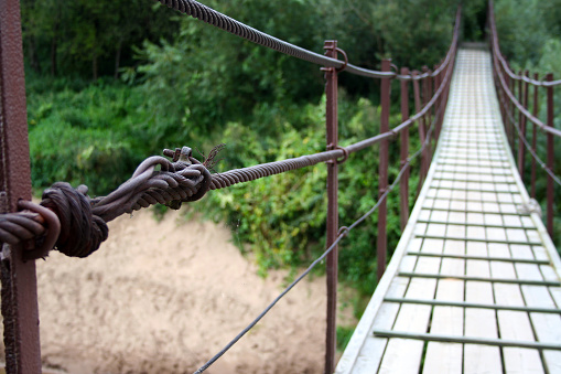 Bridge metal rope connection. Bridge across the river. Wooden bridge. Hanging over the river. Priekule in the city of Lithuania. The name of the river is Minija.
