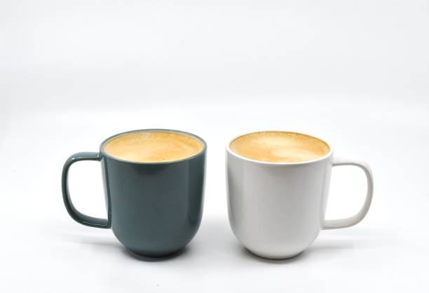 istock Two different coloured mugs of frothy hot coffee on a plain white background 1694158039