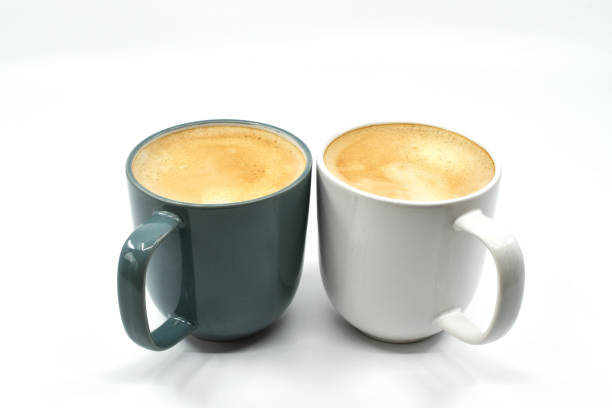 istock Two different coloured mugs of frothy hot coffee on a plain white background 1694158046