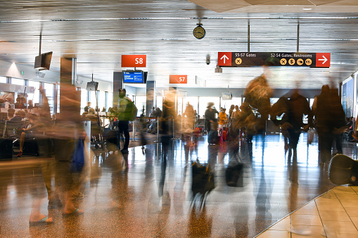 Airline Passengers are blurred in motion inside a busy terminal at the Seattle Airport.