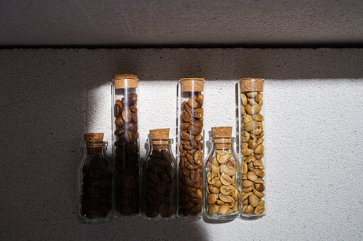 raw, light roasted and dark roasted coffee beans in small glass tubes