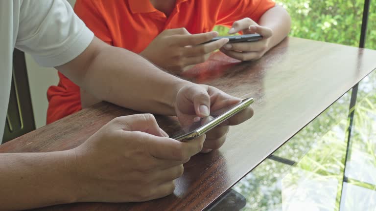 Asian father and son with mobile phone playing games together dad spend time with children