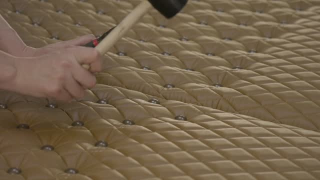hand uses mallet to tuft leather panel