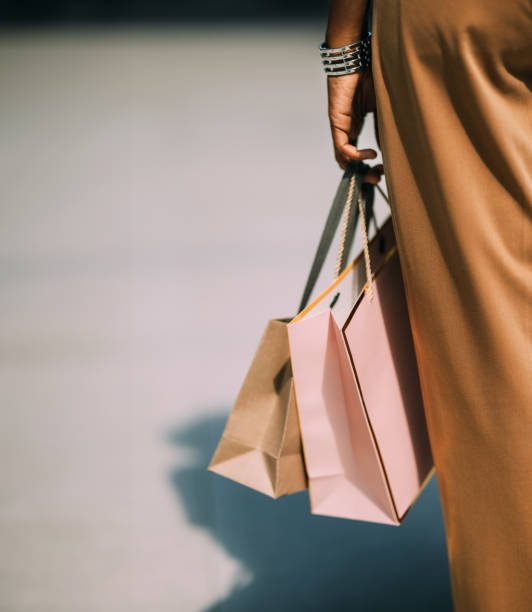 A Close Up View Of An Unrecognizable Beautiful Cuban Woman Holding Paper Bags After Going Shopping A back view of an unrecognizable Latin female with shopping bags standing on the street after being at the shopping mall. lifestyle shopping stock pictures, royalty-free photos & images