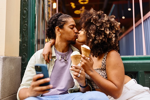 Beautiful multiracial couple kissing in the ice cream shop