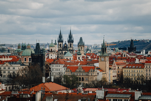 Prague, Czech Republic, 26 March 2023: Panorama of city from Petrin Hill, Red roofs, Cloudy spring day, High spires gothic towers of Church of Our Lady before Tyn, urban landscape, cathedral
