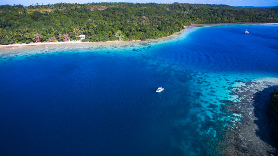 Aerial view of small boat moored over coral reef in Tonga
