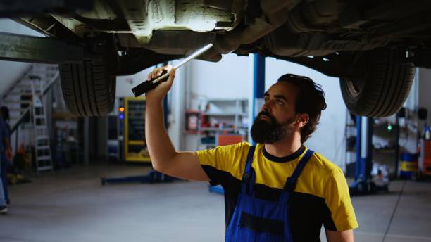 istock Expert in garage works on suspended car 1694227483