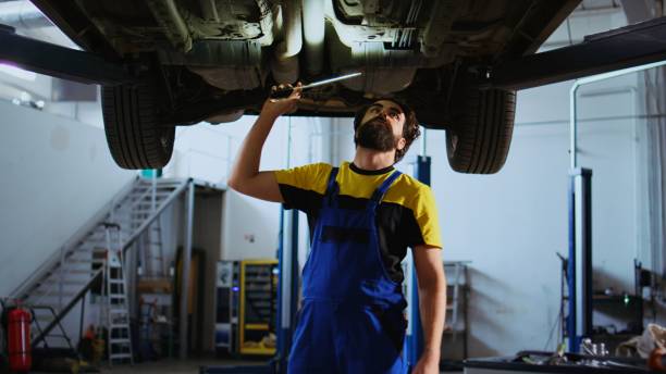 istock Man in garage works on suspended car 1694228029