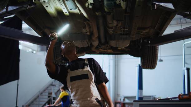 istock Garage repairman works on suspended car 1694228769