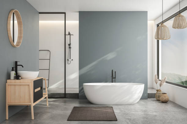 istock Modern minimalist bathroom interior, modern bathroom cabinet, white sink, wooden vanity, interior plants, bathroom accessories, bathtub and shower, white and blue walls, concrete floor. 1694234084
