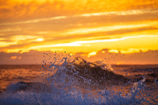 Ambient atmosphere of waves splashing with vivid golden sunrise. Photographed on the south east coast of Australia.