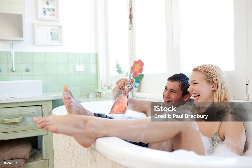 Couple in clothing drinking champagne in bathtub  Bathtub Stock Photo