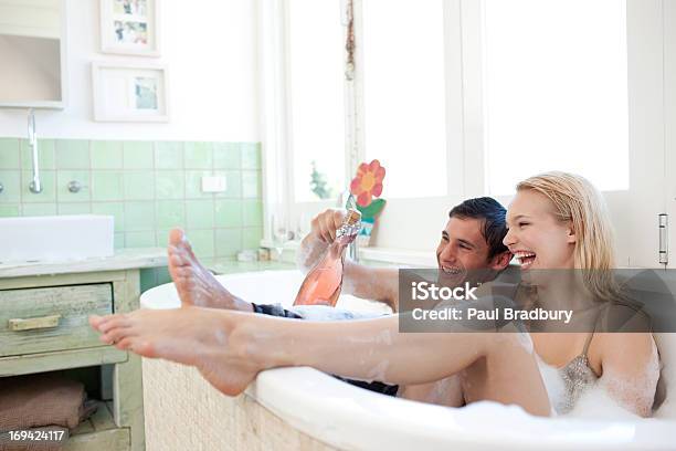 Couple In Clothing Drinking Champagne In Bathtub Stock Photo - Download Image Now - Bathtub, Two People, Bathroom
