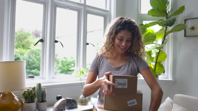Latin American cheerful woman at home looking at the packages she just received after shopping online