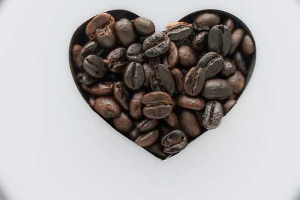 istock Love symbol with heart shaped coffee made with coffee beans White background 1694250769