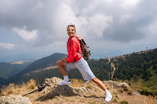 Side-view of an active young Caucasian woman, enjoying majestic hike on the mountain