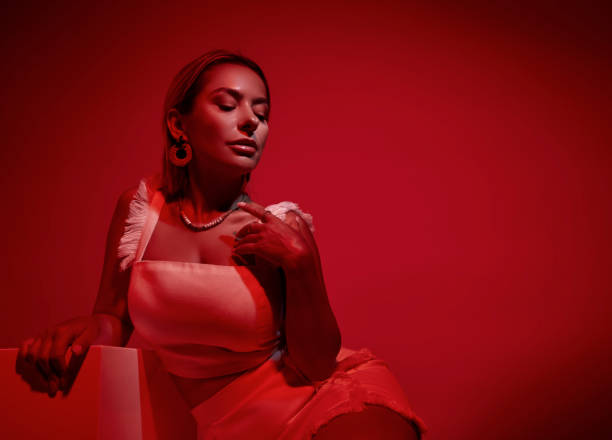 istock Woman sitting on white box in red light. 1694278617