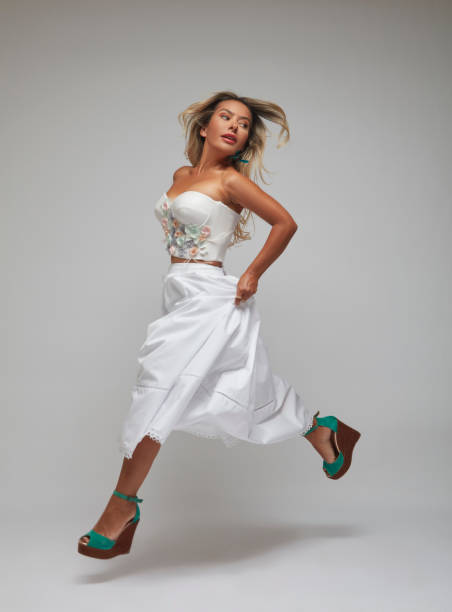 istock Woman jumping as she steps in front of a white background. 1694280771