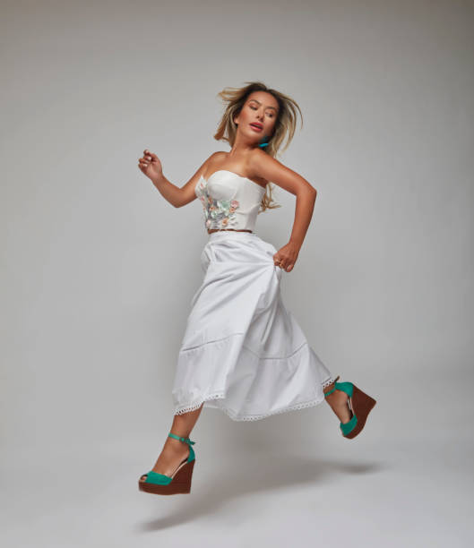 istock Woman jumping as she steps in front of a white background. 1694281302