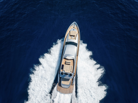 Aerial top view of a luxury yacht cruising with high speed over blue ocean